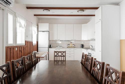 a kitchen with a table and chairs and white cabinets at CYV - A unique Villa on a Lake in Karhoinen