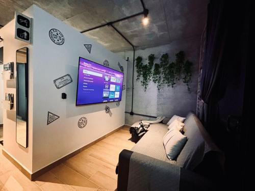 a living room with a couch and a tv on a wall at Travel VIP Lounge Themed Stay with Private Parking in Monterrey
