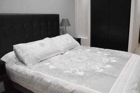 Un dormitorio con una cama grande con cabecero negro. en Apartamenticos Boggiero III, en Zaragoza