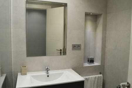 Un baño blanco con lavabo y espejo. en Apartamenticos Boggiero III, en Zaragoza