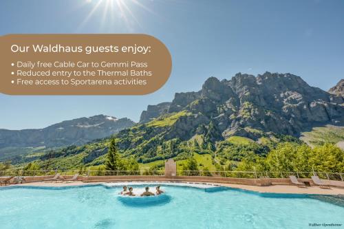 a group of people in a pool with mountains in the background at Hotel Restaurant Waldhaus in Leukerbad