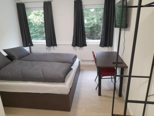 a bedroom with a bed and a table and windows at Boardinghaus Waldesruh in Lohne