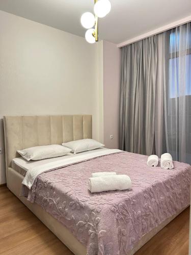 a bedroom with a large bed with towels on it at Olive Dream Apartment with Balcony View in Tbilisi City