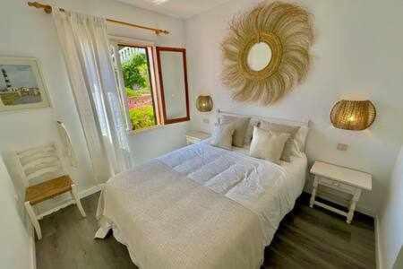 ein weißes Schlafzimmer mit einem großen Bett und einem Spiegel in der Unterkunft Ponent - Planta baja con vistas al mar y piscinas in Arenal d'en Castell