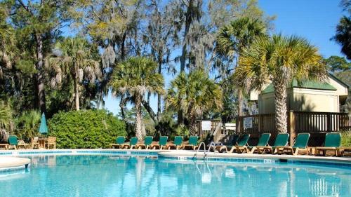 a large swimming pool with chairs and palm trees at Driftwood Villa 256 - Slo Drift in Edisto Island