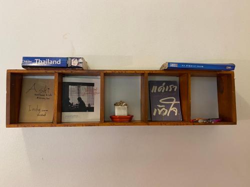 a wooden shelf on a wall with pictures on it at Ashi Guesthouse Chiangdao in Chiang Dao