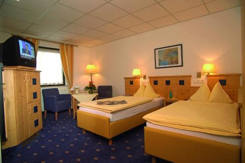 a hotel room with two beds and a television at Hotel Zum Löwen in Mörfelden-Walldorf