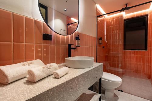 une salle de bain avec un lavabo, des toilettes et un miroir dans l'établissement Hotel Tres Altares Sabaneta, à Sabaneta