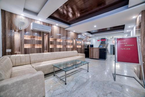 Una sala de estar con un sofá y una mesa de cristal. en Hotel O Crown Residency, en Faridabad