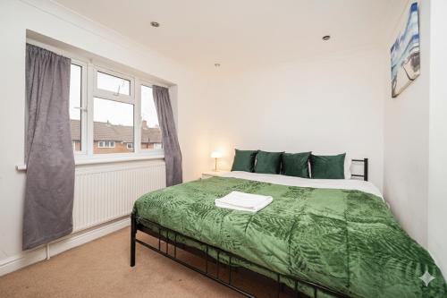 South Ruislip StationにあるFamily Friendly 3BR Haven in Northolt with Parkingのベッドルーム1室(ベッド1台、緑の掛け布団、窓付)