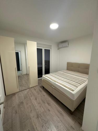 a white bedroom with a bed and a mirror at Lacky-ca in Prokuplje
