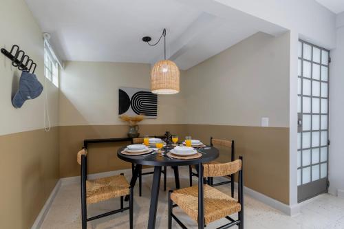 a dining room with a black table and chairs at Kin Pech Roma by Capitalia in Mexico City
