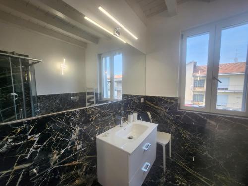 a bathroom with a white sink and black marble walls at Residence Jasmin 2P B in Turate