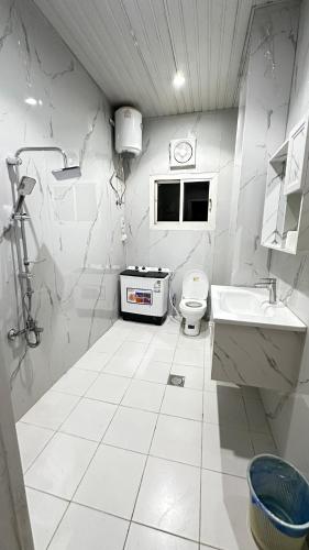 a white bathroom with a toilet and a sink at شقق نرمادا المفروشه402 in Medina