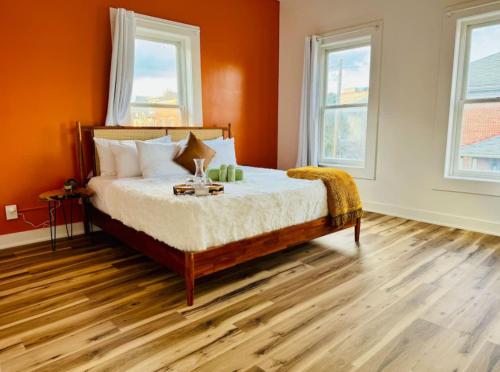 a bedroom with a bed with orange walls and wooden floors at Short North Convention King Bed Free Parking! in Columbus
