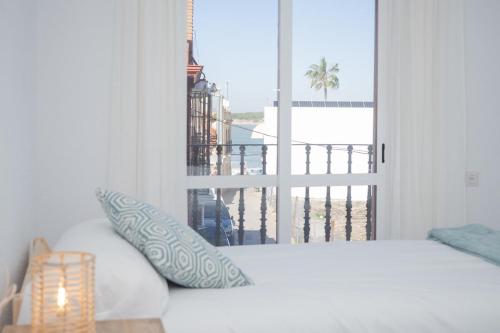 a bedroom with a bed and a view of a balcony at Casa Salmedina in Sanlúcar de Barrameda