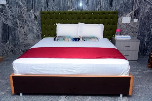 a bedroom with a large bed with a green headboard at Gugan home stay in Tiruchchendūr