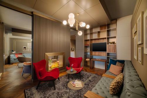 a living room with red chairs and a couch at NH Collection Milano Touring in Milan