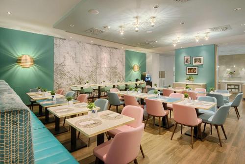 Un comedor con mesas y sillas rosas. en NH Collection Milano Touring, en Milán