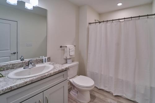 a white bathroom with a toilet and a sink at The Ruby 313 By Avada Properties in Pigeon Forge
