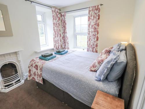 a bedroom with a bed and a fireplace at Smithy Cottage at Bowland Bridge in Bowland Bridge
