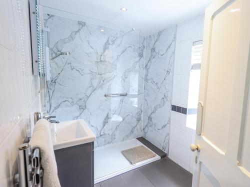 a bathroom with a marble shower and a sink at Smithy Cottage at Bowland Bridge in Bowland Bridge