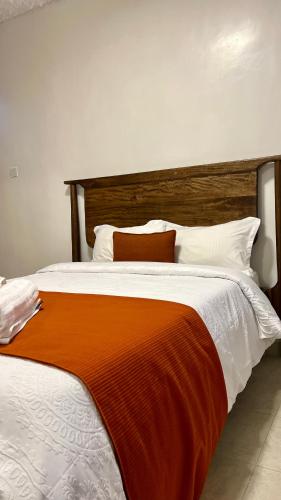 een groot bed met een oranje deken erop bij Nanyuki Luxe Stays 2 in Nanyuki