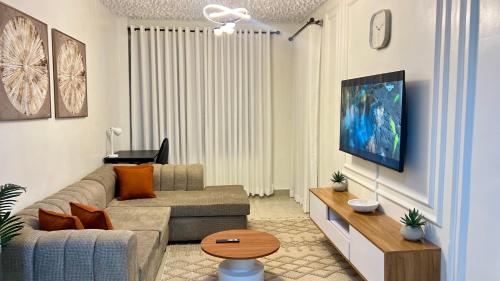 een woonkamer met een bank en een tv bij Nanyuki Luxe Stays 2 in Nanyuki