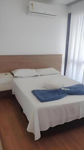 a large white bed with a blue shirt on it at Ed Highline, piscina, lavanderia in Joinville