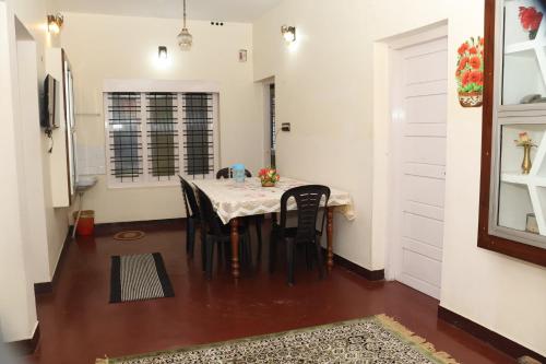 a dining room with a table and black chairs at GEE VEE Home Stay in Munnar
