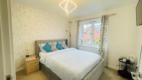 a bedroom with a bed with blue pillows and a window at The Guest Nook - Wollaton in Nottingham