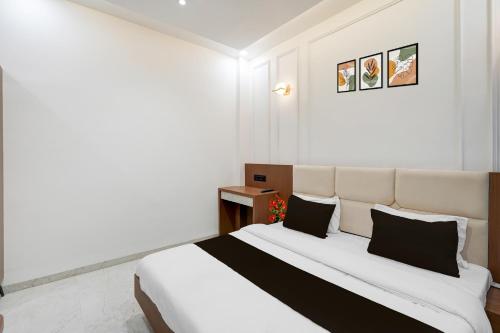 1 dormitorio con 1 cama blanca grande con almohadas negras en Collection O Ujjain Central Railway Junction Formerly Hotel Jai Jagdish, en Ujjain