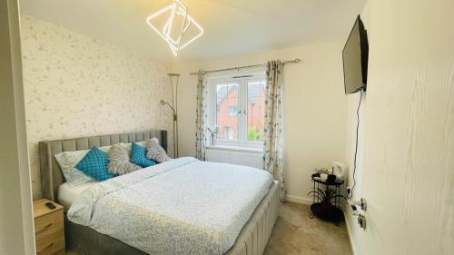 a bedroom with a bed with blue pillows and a window at The Guest Nook - Wollaton - Room and Private Bathroom in the house in Nottingham