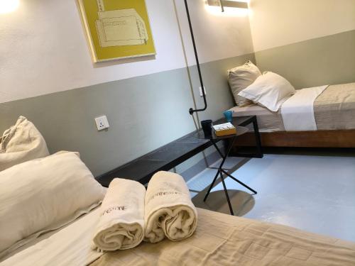 two beds in a room with towels on the beds at The Brownstone Hostel & Space in Ipoh