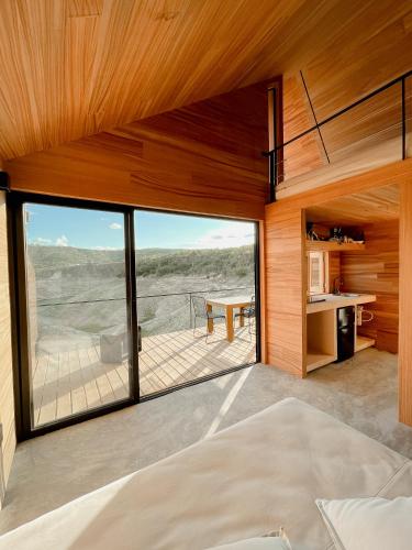 Blick aus dem Wohnzimmer eines Hauses mit einem großen Fenster in der Unterkunft Wander Cabins Dehe in Banzhá
