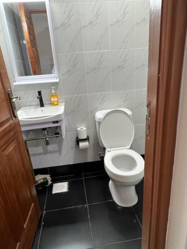 une salle de bains avec toilettes, lavabo et miroir dans l'établissement Favour cozy stay 24, à Nairobi