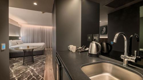 a bathroom with a sink and a bed in a room at The Rockefeller Hotel Cape Town in Cape Town