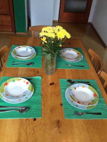 a wooden table with plates and a vase of flowers at Bella Vista in Vrchlabí