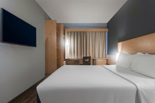 ein Schlafzimmer mit großem Bett und Flachbildfernseher in der Unterkunft Ibis Salvador Rio Vermelho in Salvador