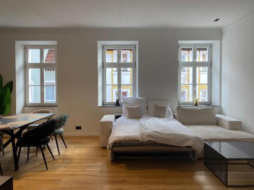 a bedroom with a bed and a table and windows at NAMASTÉ Homes - Luxus-Apartment mit Whirlpool & Garage in Bad Windsheim