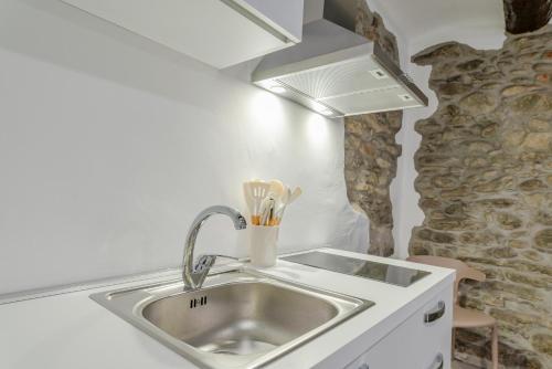 a kitchen sink with utensils in front of a stone wall at La Dimora delle Masche in Levone