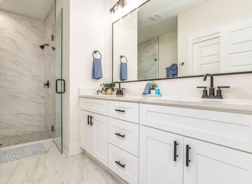 a white bathroom with two sinks and a shower at Downtown Sea Escape in Pensacola