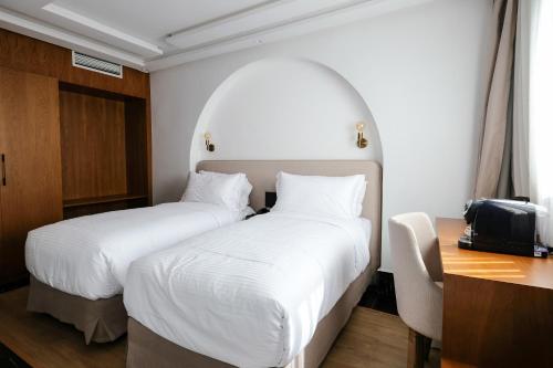 a hotel room with two beds and a desk at Chic Hotel in Rabat