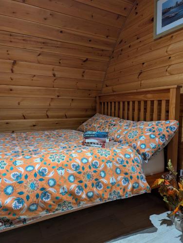 a bed in a room with a wooden wall at Rose Glamping pod in Derrylin