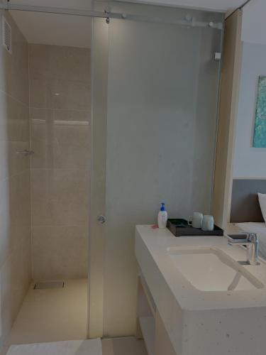a white bathroom with a shower and a sink at The Arena Resort Beach Front View LightA-0441 in Cam Ranh International Airport