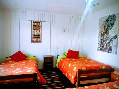 a bedroom with two beds with red sheets at Hospedaje Luna in Valdivia