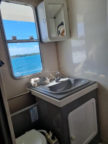 a small bathroom with a sink and a window at catamaran nautilodge in Sainte-Anne