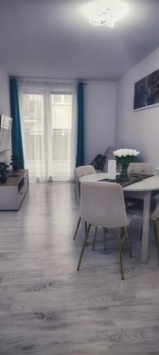 Una sala de estar con una mesa y sillas y un sofá. en Kapi Royal Apartament, en Świnoujście
