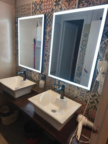 a bathroom with two sinks and two mirrors at Buba House - Women Only Hostel in Barcelona