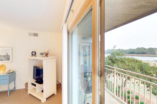 a room with a balcony with a tv and a window at Bluff Villas 1733 in Hilton Head Island
